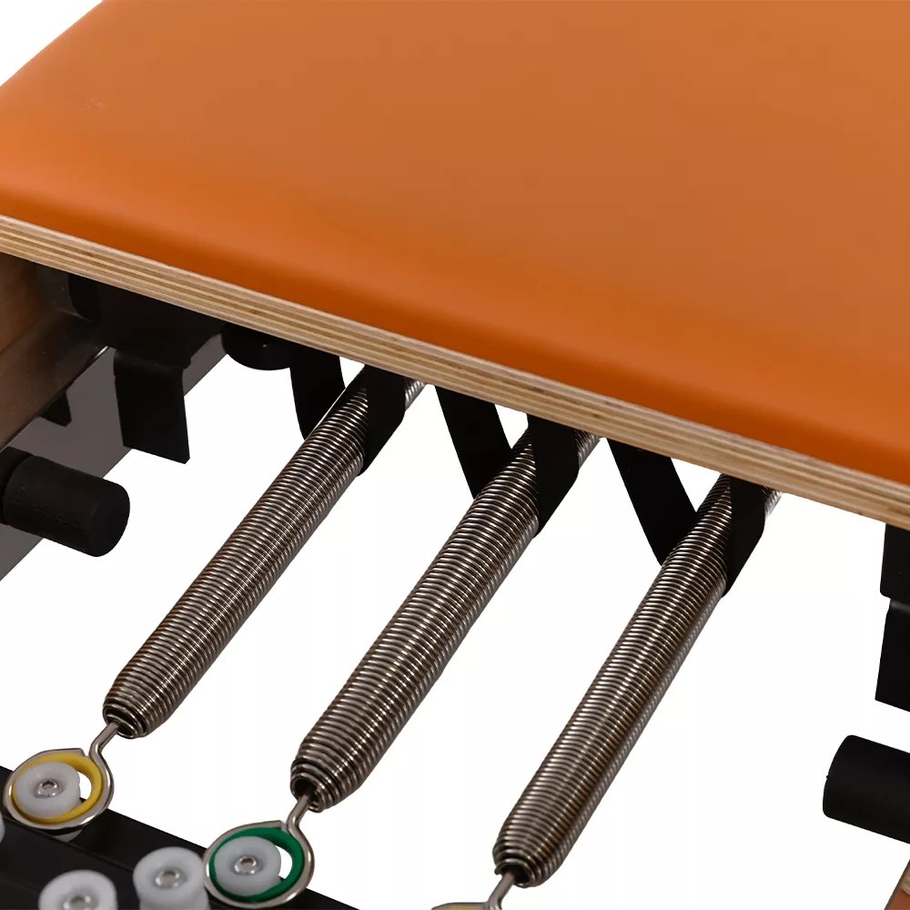 Children Pilates reformer spring system under orange carriage Children Pilates reformer spring system under orange carriage